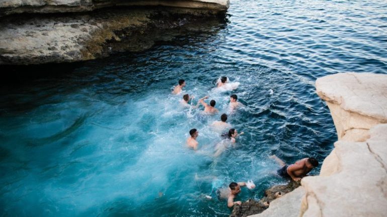 People in a natural swimming pool with rocky area around